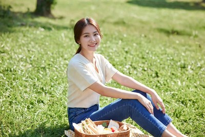 Asian woman with picnic basket in grass