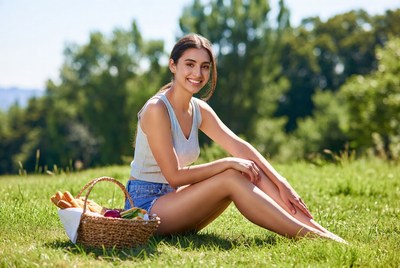 Smiling woman with picnic basket on grass