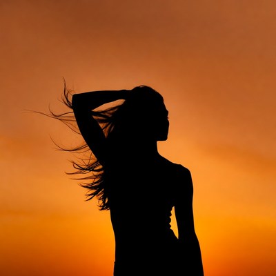Woman silhouette with flowing hair at sunset