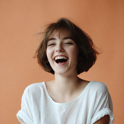 Young woman laughing on orange background