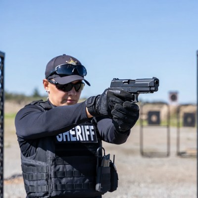 Female sheriff aiming handgun at range