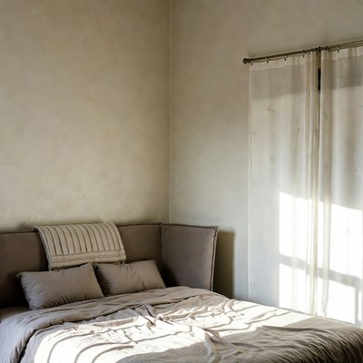 Empty Bed in Sunlit Corner Room