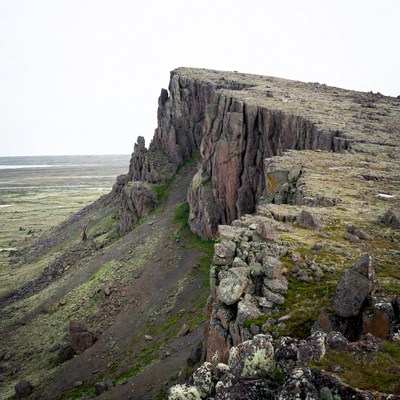 Steep rocky cliff over tundra plain
