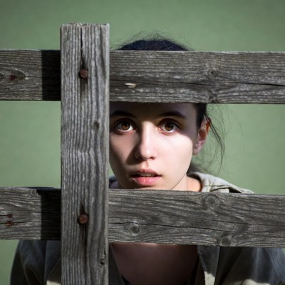 Woman peeking through wooden fence