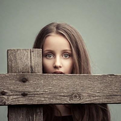 Girl peeking over wooden fence