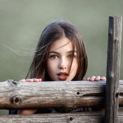 Girl peeking over wooden fence