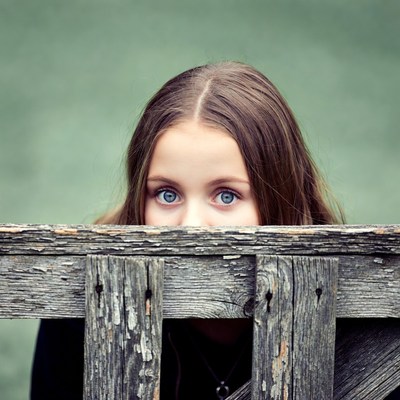 Girl peeking over wooden fence