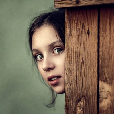 Girl peeking through wooden fence