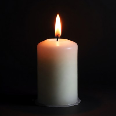 Burning white candle on black background