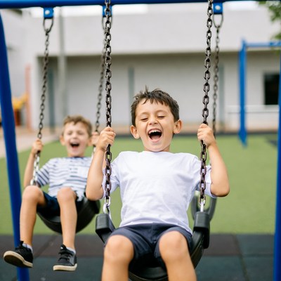 Two boys swinging on playground swings