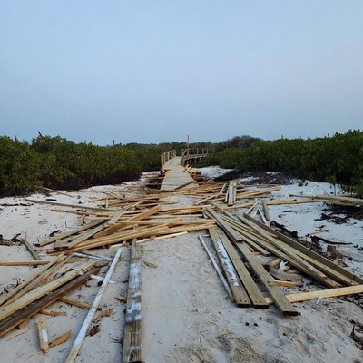 Damaged boardwalk amid beach debris