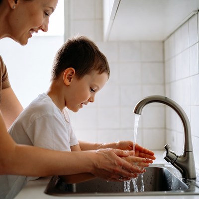 Mother helping boy wash hands