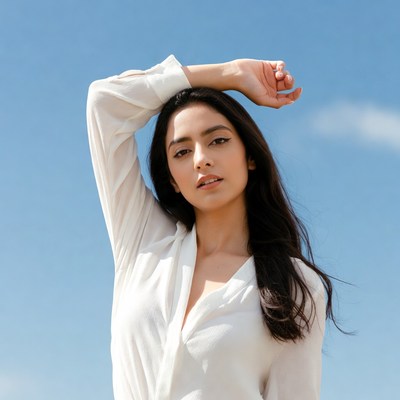 Woman raising arm against blue sky