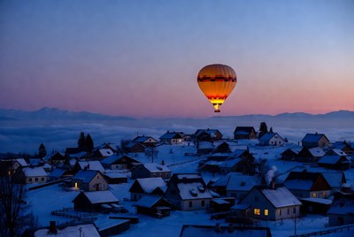 Hot air balloon over snowy mountain village