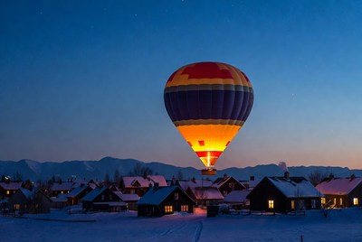 Hot air balloon over snowy mountain village