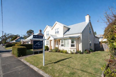Cream house with For Sale sign