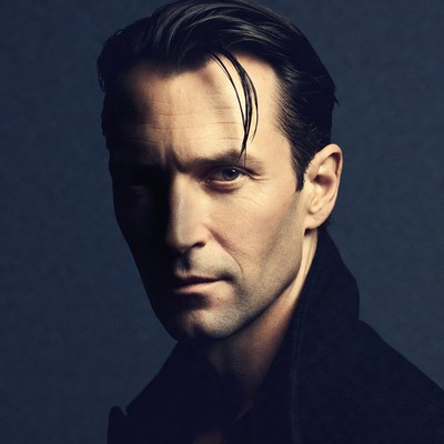 Man with slicked-back hair in dark coat