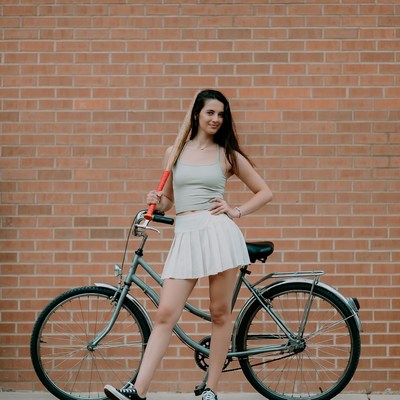 Woman posing with bat on bicycle