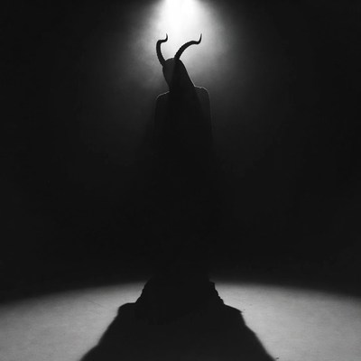 Silhouetted demon with horns in spotlight