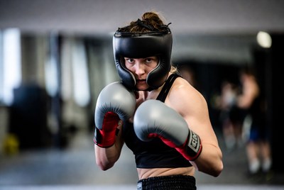 Female boxer in headgear with gloves
