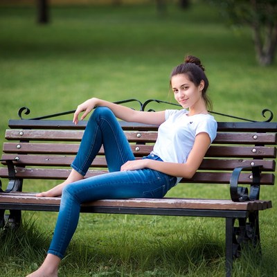 Teen girl lounging on park bench