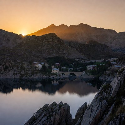 Sunset over mountain lake and stone bridge