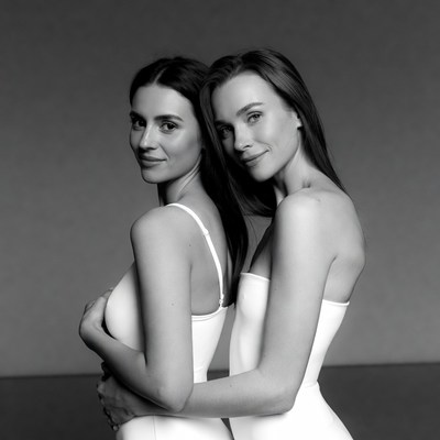 Two women embracing in white dresses