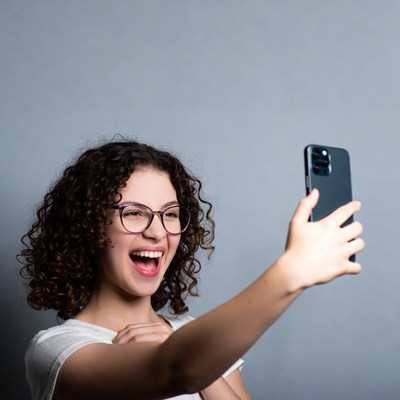 Smiling woman taking selfie with iPhone
