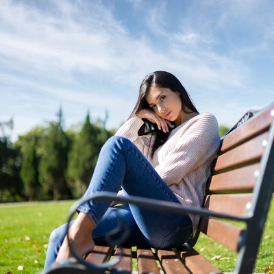 Asian woman sitting on park bench