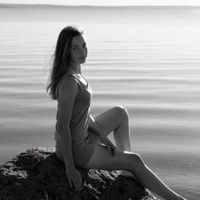Teen girl smiling on lakeside rock