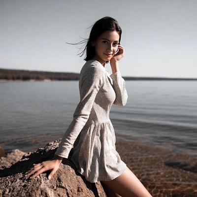 Woman in dress sitting on rock by lake