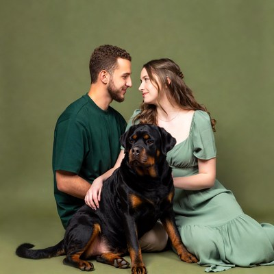 Couple embracing Rottweiler dog