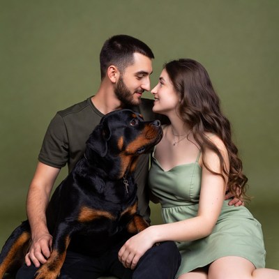 Couple embracing Rottweiler dog
