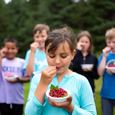 Girl eating lingonberries with kids outdoors