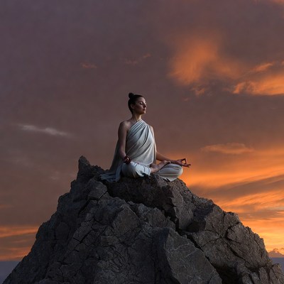 Woman meditating on mountain peak
