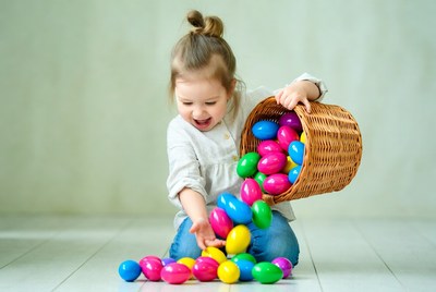 Toddler girl spilling colorful Easter eggs