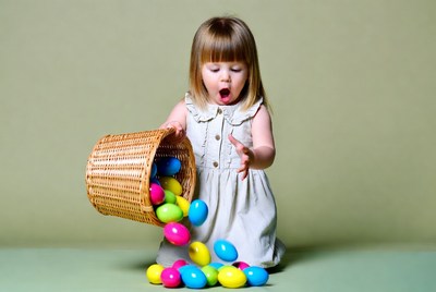 Toddler girl spilling colorful Easter eggs