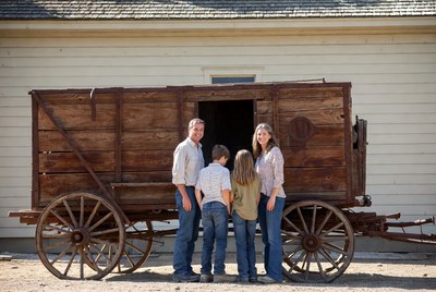 Family standing by wooden covered wagon