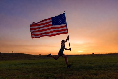 Woman running with American flag at sunset