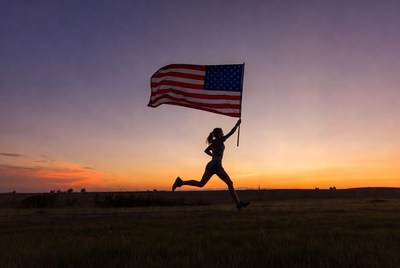 Woman running with American flag at sunset