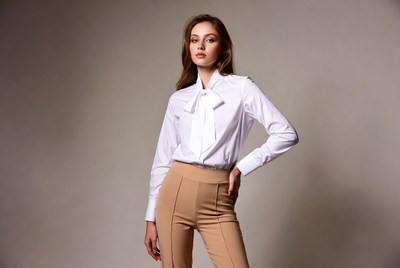 Woman in white bow blouse tan pants