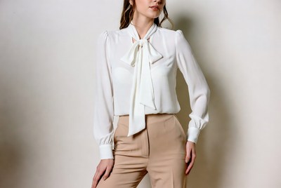 Woman in white bow blouse and beige pants