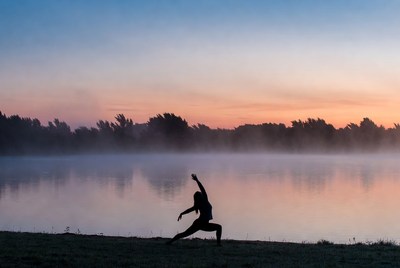 Silhouette woman doing yoga by lake