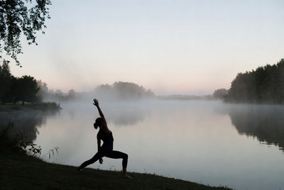 Woman doing yoga pose by misty lake