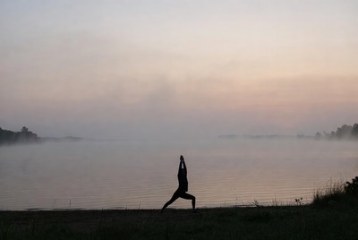 Silhouette woman practicing yoga by lake