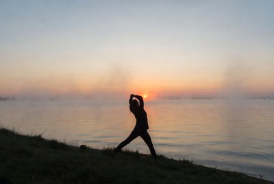 Silhouette woman yoga pose at sunset lake