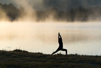 Silhouette woman doing yoga by misty lake