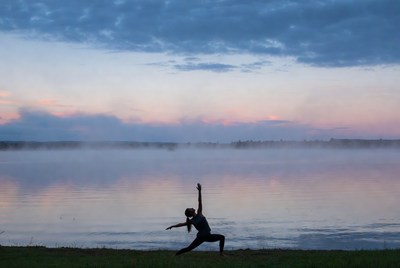 Woman doing yoga by misty lake