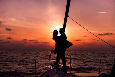Silhouette couple kissing on yacht at sunset