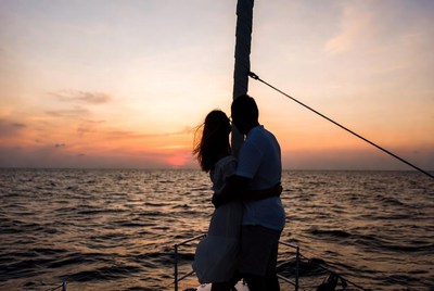 Silhouette couple kissing on sailboat at sunset